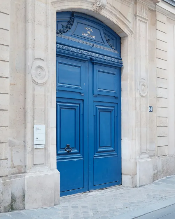 La porte d’entrée du cabinet, bleue, dans une façade de pierre claire