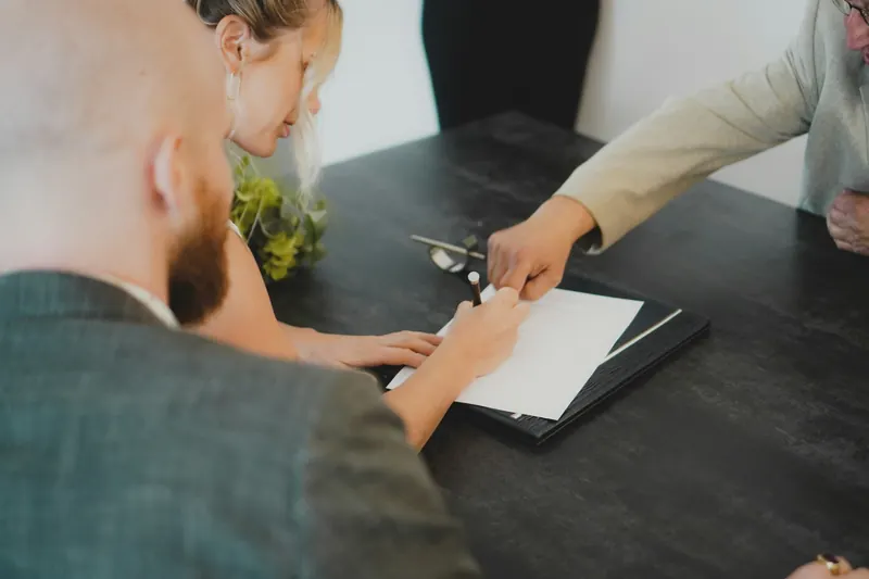 Un avocat et une cliente penchés sur un document, autour d’une table sombre