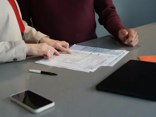 Deux personnes relisent des documents posés sur une table grise